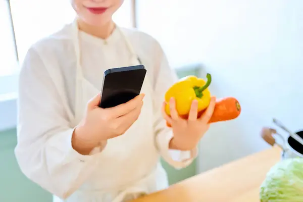 Junge Frau Holt Gemüse Und Smartphone Der Küche — Stockfoto