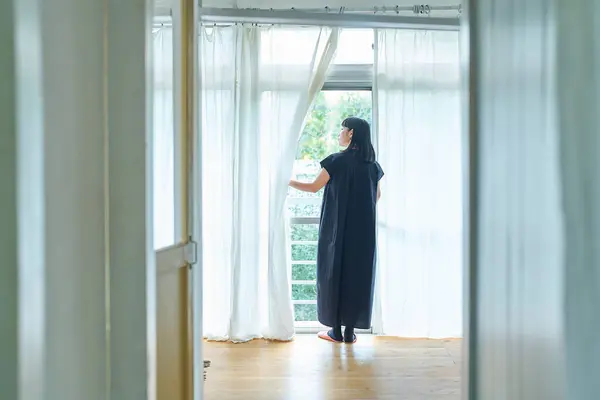 Junge Frau Öffnet Die Spitzenvorhänge Und Schaut Aus Dem Fenster — Stockfoto