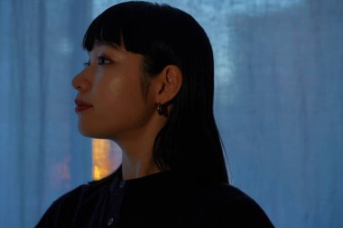 Gün batımında pencerenin kenarında dinlenen genç bir kadın.