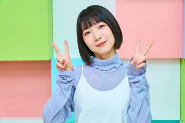 Genç kadın kameraya bakıyor ve barış işareti yapıyor.