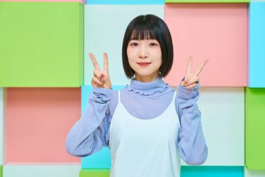 Genç kadın kameraya bakıyor ve barış işareti yapıyor.