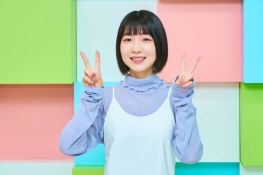 Genç kadın kameraya bakıyor ve barış işareti yapıyor.