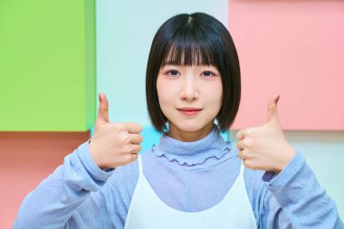 Baş parmak pozu veren genç bir kadın.