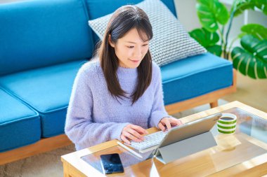 Sıradan bir odada bilgisayarda çalışan bir kadın.