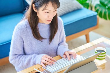 Sıradan bir odada bilgisayarda çalışan bir kadın.