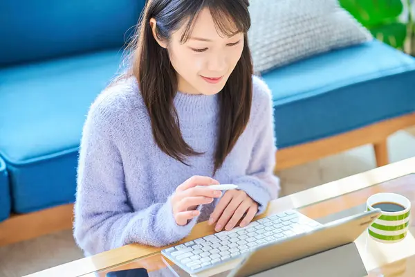 Sıradan bir odada bilgisayarda çalışan bir kadın.