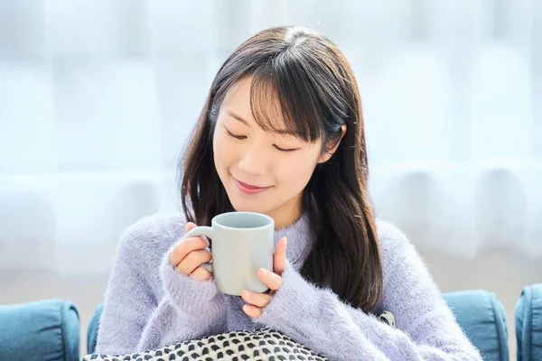 A woman holding a mug and looking relaxed