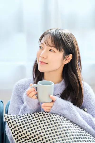 A woman holding a mug and looking relaxed