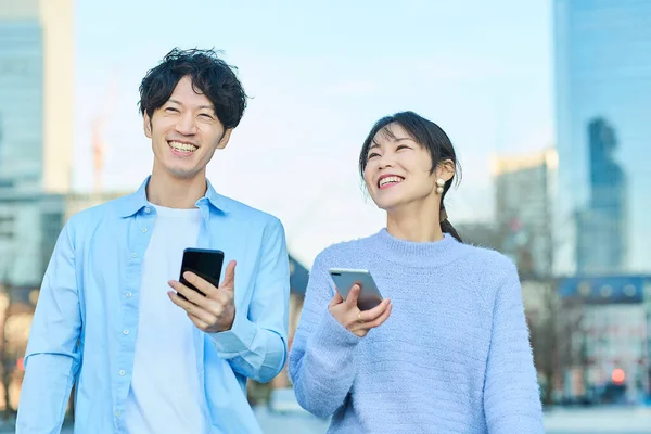 在晴朗的日子里拿着智能手机微笑的男人和女人 — 图库照片