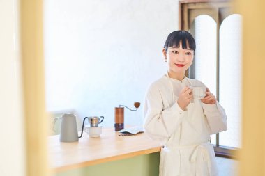 Mutfakta kahve fincanı olan genç bir kadın.