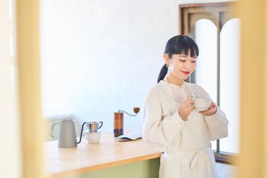 Mutfakta kahve fincanı olan genç bir kadın.