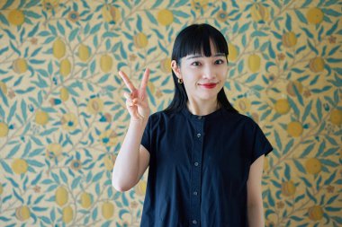 Genç kadın gülümsüyor ve odada barış işareti yapıyor.