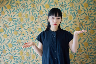 Genç bir kadın odada iki seçeneği karşılaştırır gibi poz veriyor.