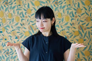 Genç bir kadın odada iki seçeneği karşılaştırır gibi poz veriyor.