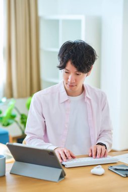 Gündüz vakti odasında bilgisayar kullanan genç bir adam.