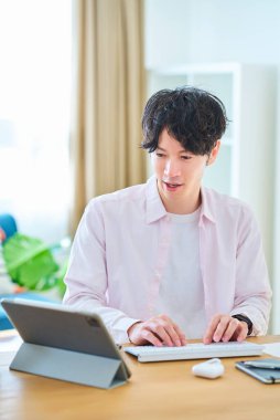 Gündüz vakti odasında bilgisayar kullanan genç bir adam.