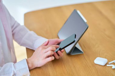 Tablet bilgisayar kullanan bir adamın elleri ve bir odada akıllı telefon.