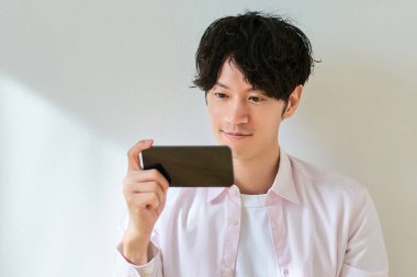 Beyaz arka planda akıllı telefon ekranına bakan genç adam