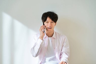 Beyaz arka planda akıllı telefondan konuşan genç adam.