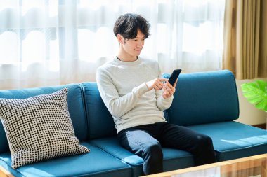 Elinde akıllı telefon tutan genç bir adam.