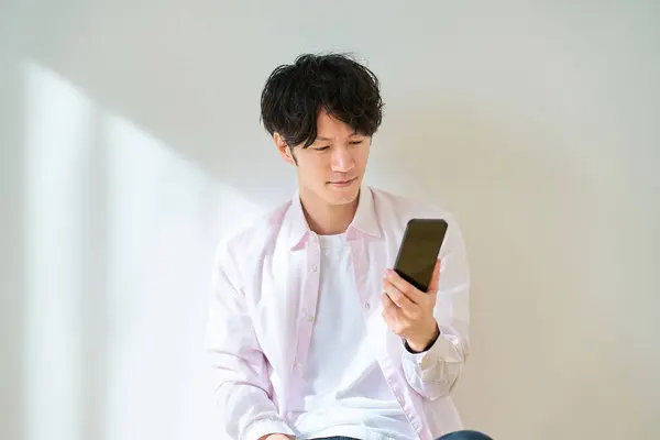 Mladý Muž Drží Smartphone Uvnitř — Stock fotografie