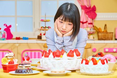 Odada şekerlerle çevrili genç bir kadın.