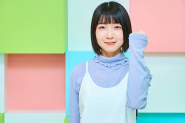 Renkli bir arka plan, genç bir kadın yumruk pompası yapıyor.