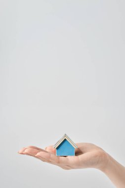 Bir kadının elinde ve beyaz arka planda tutulan bir ev modeli.