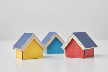 Beyaz bir masanın üzerine dizilmiş birden fazla evin modelleri.