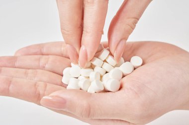 avuç içi ve beyaz arka planda bir sürü hap