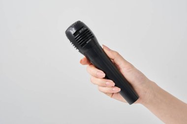 Kablosuz mikrofon ve beyaz arka plan tutan bir kadın eli.