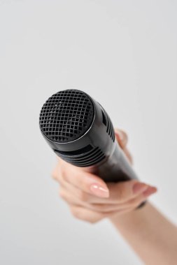 Kablosuz mikrofon ve beyaz arka plan tutan bir kadın eli.