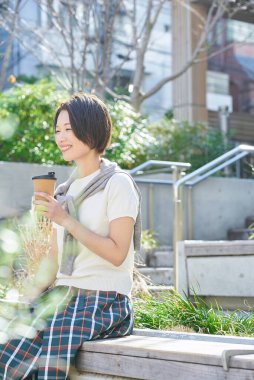 Kadın dışarıda kahve içerken rahatlamış görünüyor.