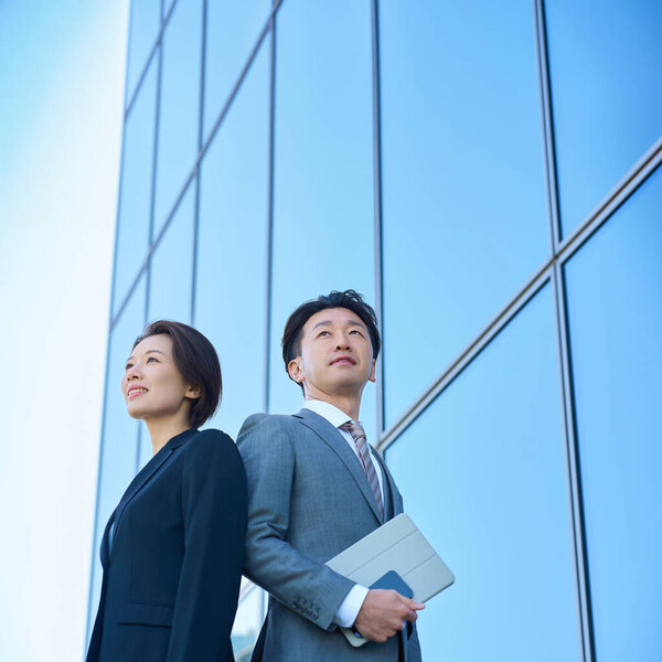 Man and woman in suits and modern architecture on fine day