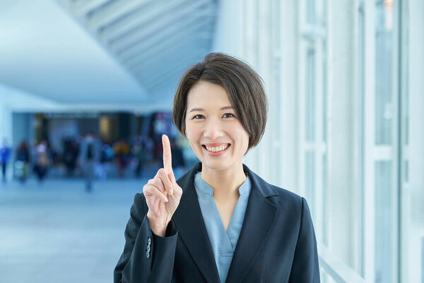 A business woman smiling and raising her index finger