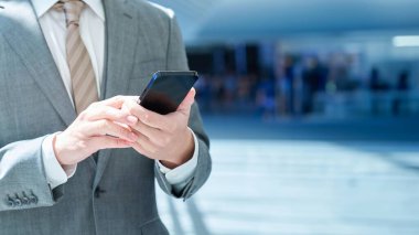 Açık havada akıllı telefon kullanan bir iş adamının eli.