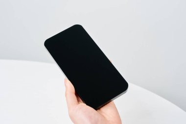 Akıllı telefon ve beyaz arka plan taşıyan bir kadının eli
