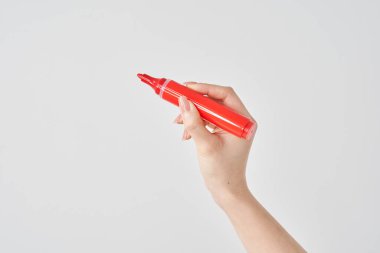 Kadının eli kırmızı kalem ve beyaz arka plan tutuyor.