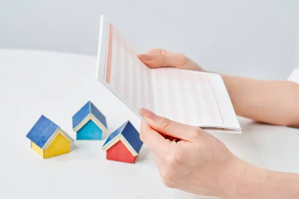 stock image model of house and woman holding bank account book