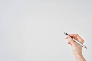 Beyaz arka plan, elinde siyah tükenmez kalem tutan kadın eli.