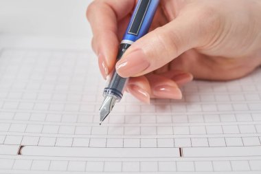 Kadın eli dolmakalem ve el yazması kağıt tutuyor.