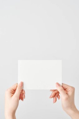 Bir kadının elleri iki elinde de boş bir kağıt ve beyaz bir arkaplan tutuyor.