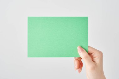 Elinde yeşil kağıt ve beyaz arka plan tutan bir kadın.