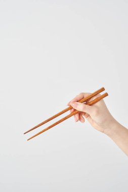 Çubuk tutan ve beyaz arka planı olan bir kadının eli.