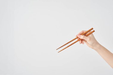 Çubuk tutan ve beyaz arka planı olan bir kadının eli.