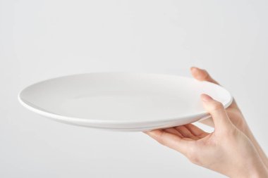 Kadının eli boş bir tabak ve beyaz bir zemin tutuyor.