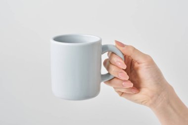 Kadın eli kupa ve beyaz bir arka plan tutuyor.