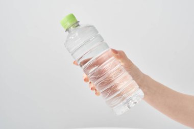 Bir kadının eli plastik bir şişe su tutuyor.