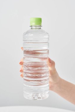 Bir kadının eli plastik bir şişe su tutuyor.