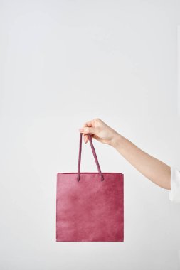 Elinde kağıt torba ve beyaz arka plan tutan bir kadın.